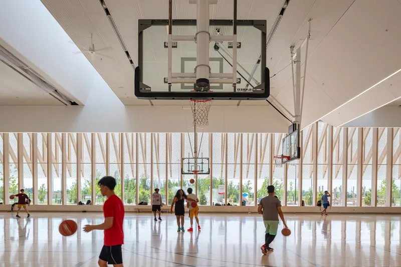 Indoor basketball court with vertical timber screen walls and players under overhead hoops
