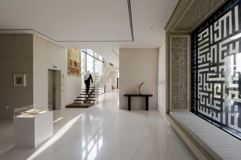 Entrance hall with floating timber staircase and geometric perforated screen filtering afternoon light
