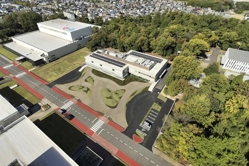 Aerial view of the white-roofed building surrounded by sculpted landscape mounds and mature tree canopy