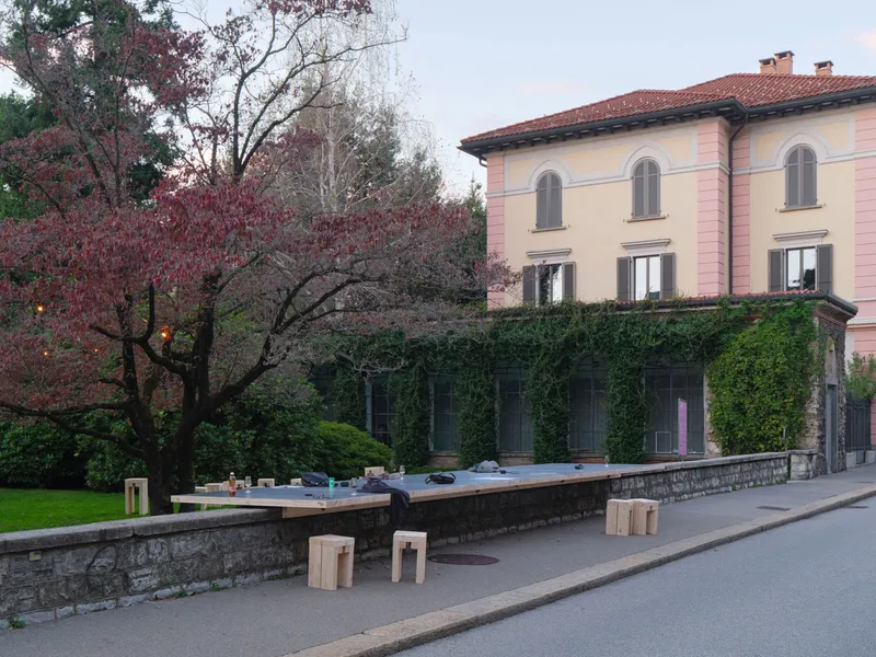 Ivy-covered facade with arched windows behind a stone wall and autumn tree at twilight