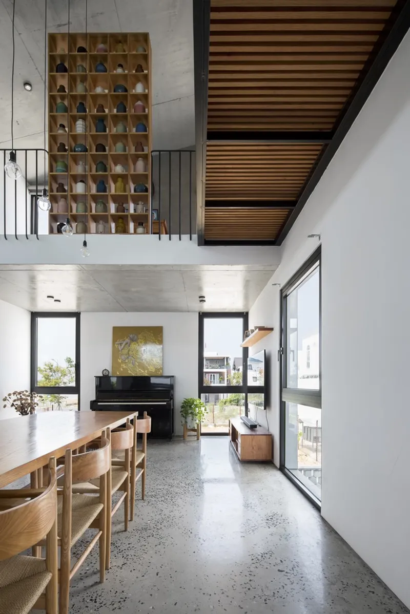 Double-height living space with timber slat mezzanine overhang and polished concrete floor