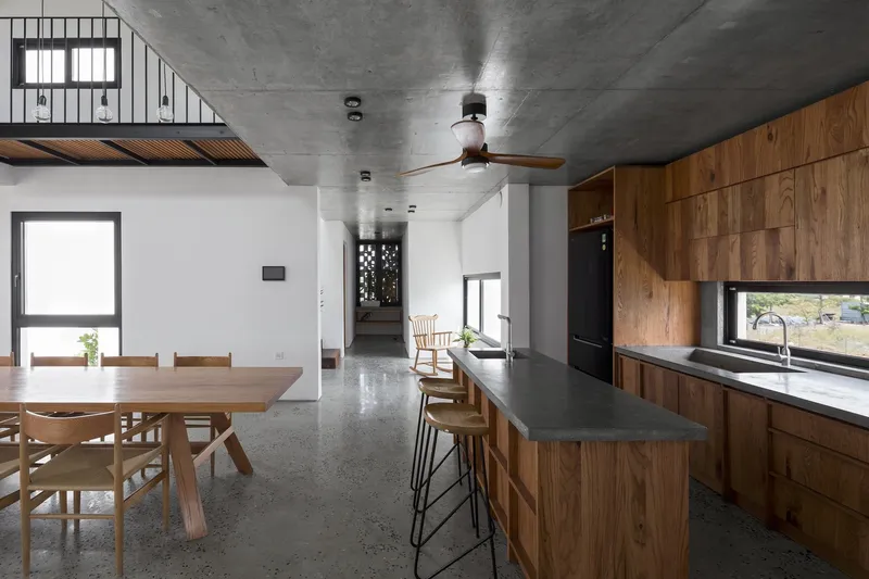 Open-plan kitchen and dining area with timber cabinetry, terrazzo flooring and exposed concrete ceiling with ceiling fan