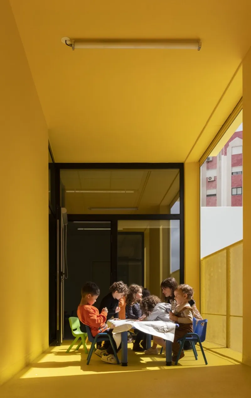 Yellow covered terrace with children gathered around a low table in bright sunlight