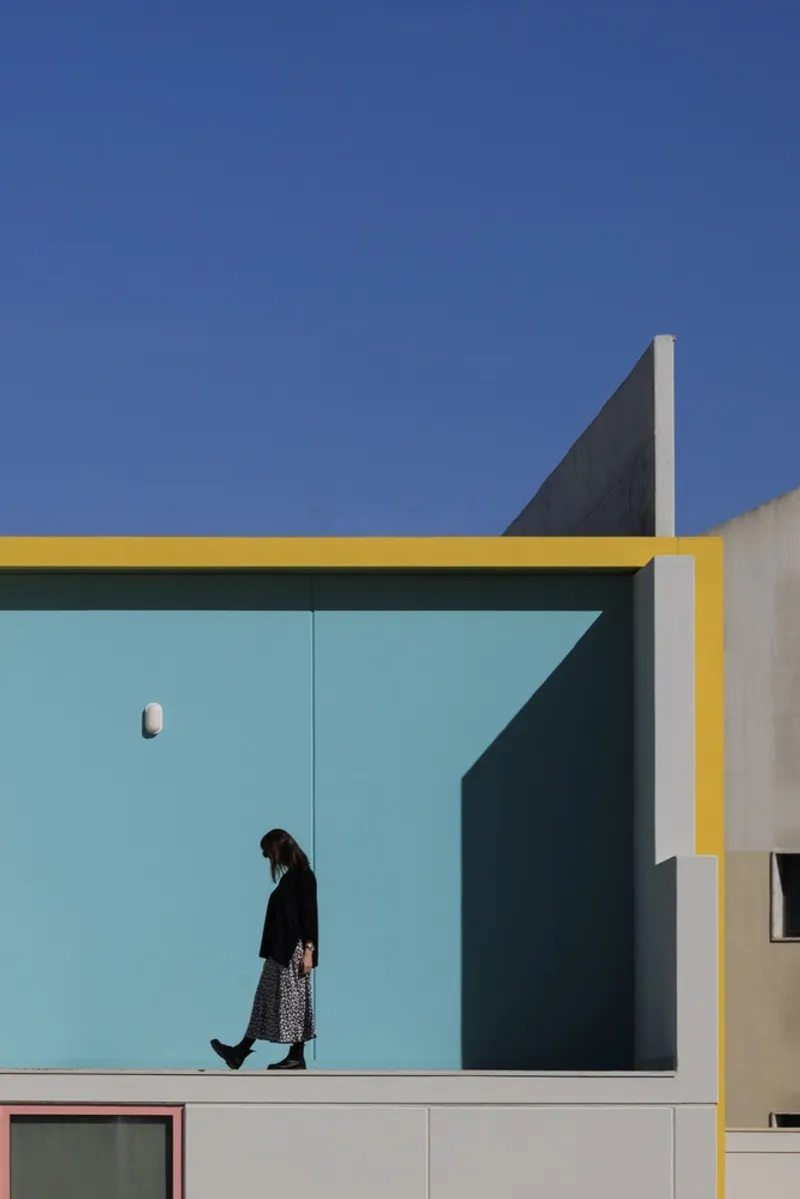 Upper terrace with turquoise panels and yellow trim as a person walks in shadow