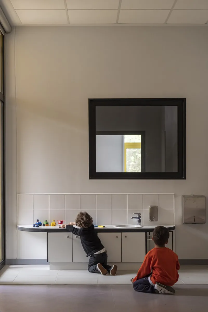 White tiled room with square window and two children at the counter and on the floor