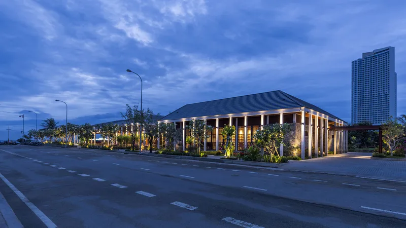 Colonnade pavilion with timber slat screens and uplighting along a street at dusk