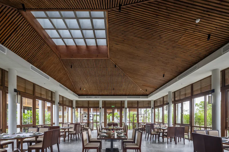 Dining space with timber slat ceiling and central skylight grid above set tables