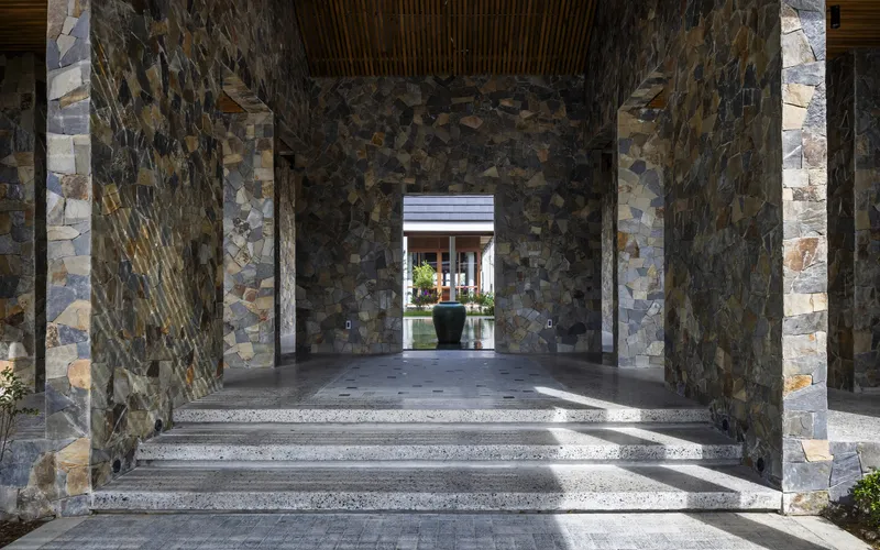 Entry vestibule with mosaic stone-clad columns framing a view through successive thresholds
