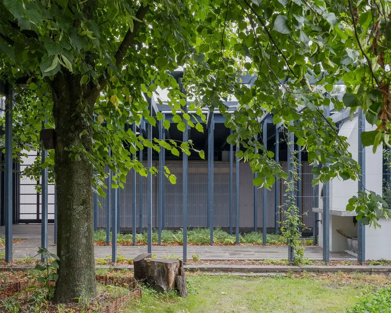 View of the vertical steel screen and corrugated wall through overhanging tree branches in autumn