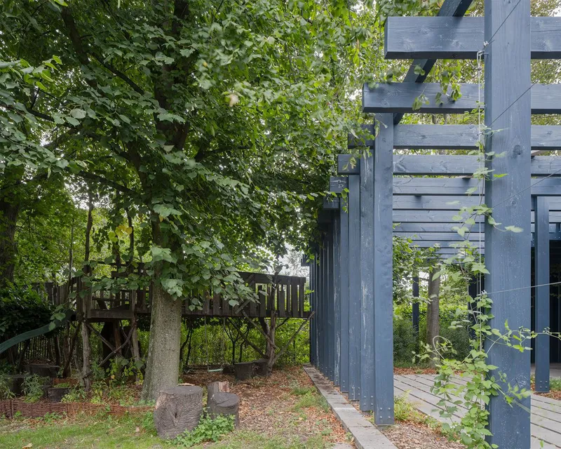 Detail of steel column connections and timber decking edge beside mature trees and fallen leaves