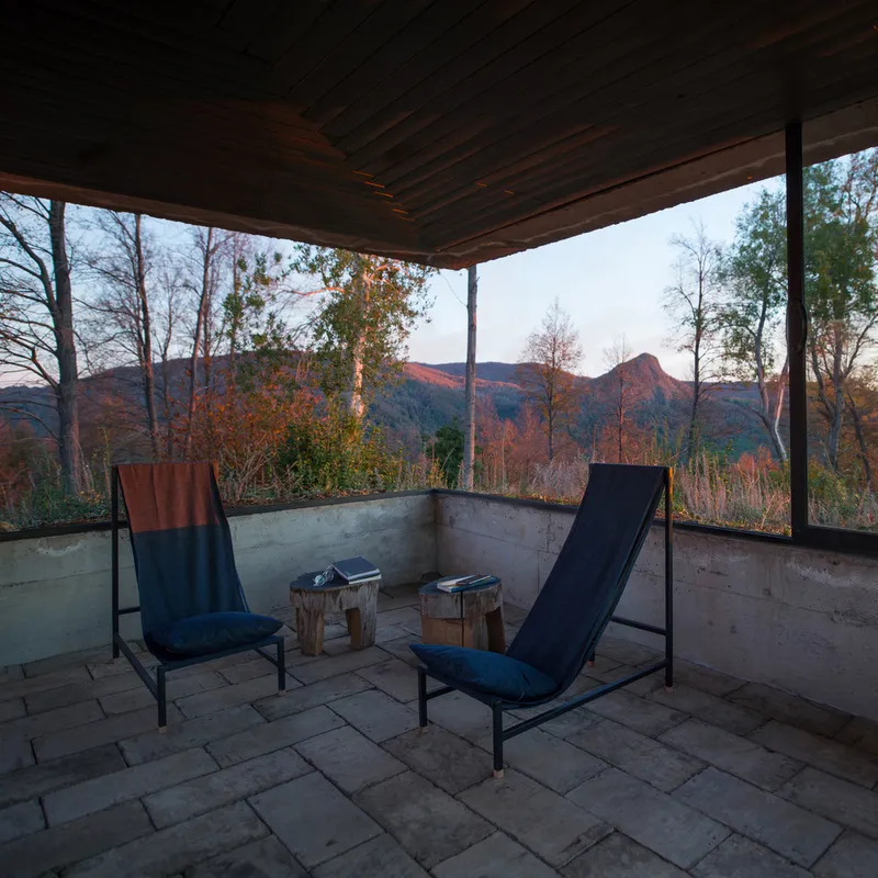 Terrace seating area with two loungers facing the mountain landscape through the open pavilion frame