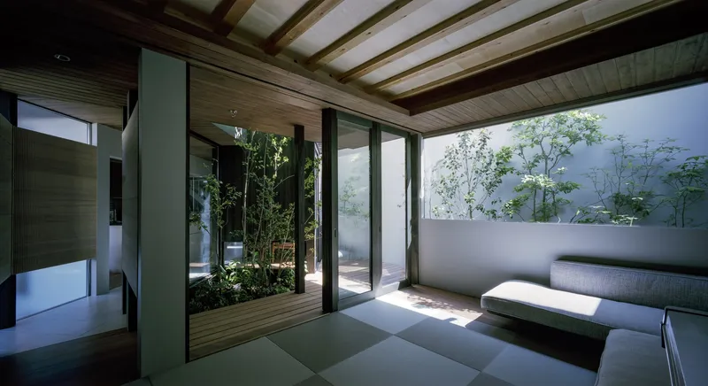 Interior room with exposed timber beams and tatami flooring opening onto a timber deck courtyard with bamboo