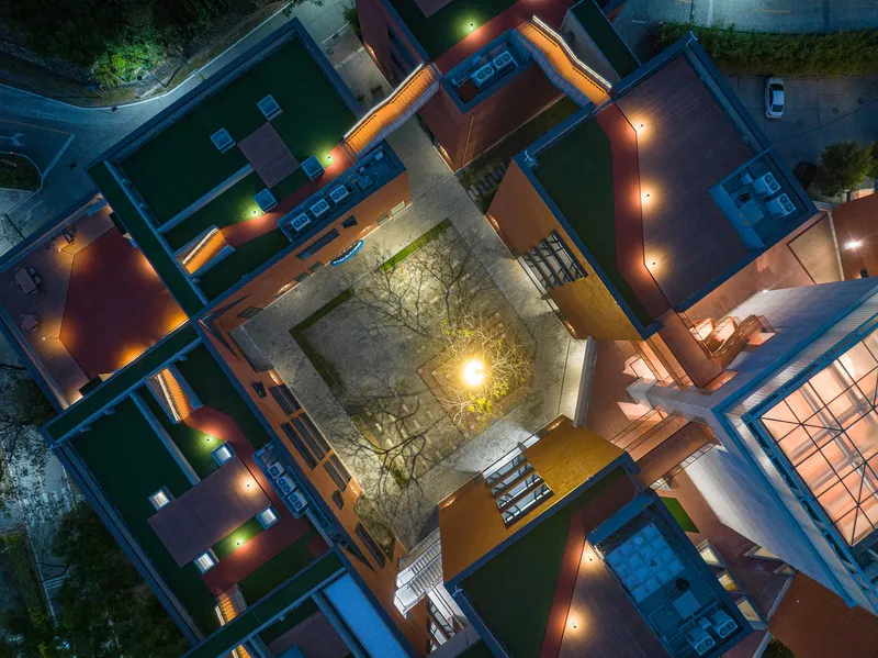 Overhead view of a central courtyard with a single illuminated tree at night
