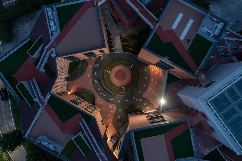 Aerial view of a circular sunken courtyard surrounded by red-roofed buildings at dusk