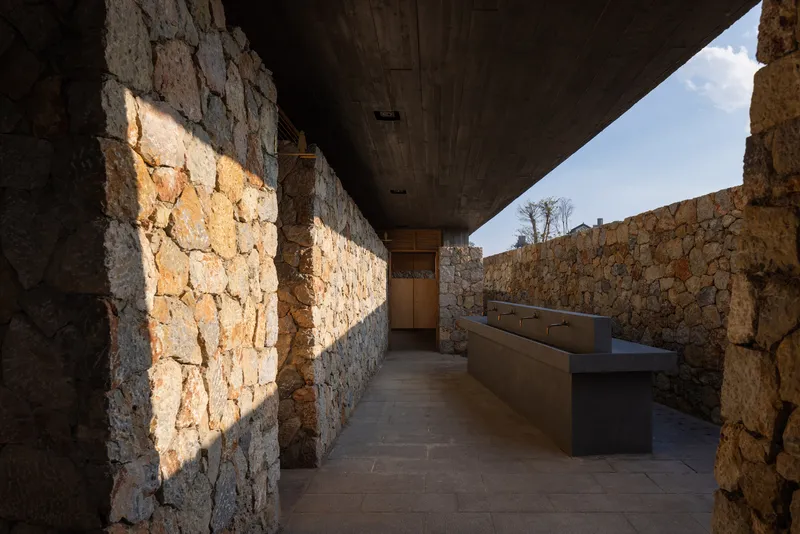 Narrow corridor flanked by dry-stacked stone walls with sunlight washing across the surfaces