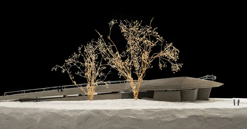 Physical model showing a low-slung roof form with preserved trees in a snowy landscape