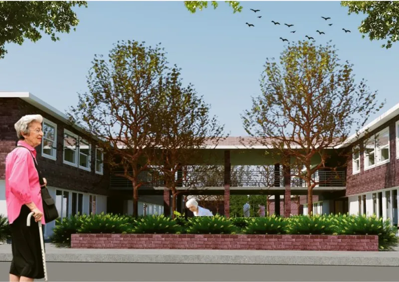 Courtyard view framed by two mature trees with an elevated walkway bridge and brick planter beds