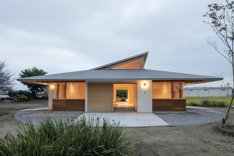 Low-pitched roof with angular skylight projection above a timber and white facade at dusk