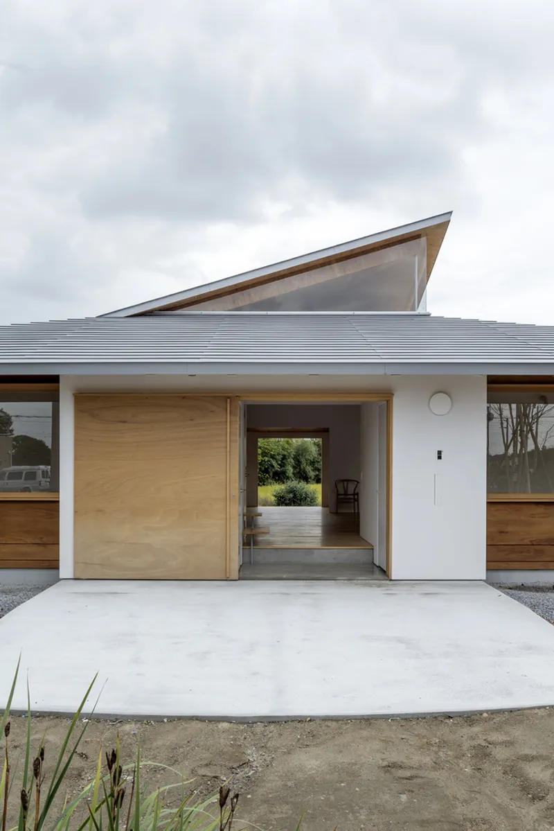 Entry facade with sliding timber door and view through to rear garden under overcast sky