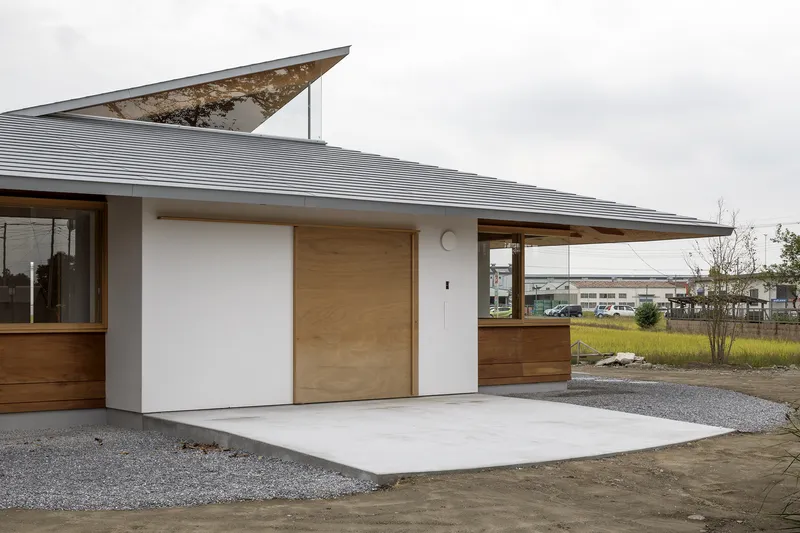 Exterior terrace with corrugated metal roof and angular skylight element rising above the roofline