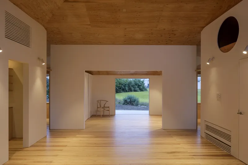Interior view through framed openings and timber ceiling toward a garden beyond