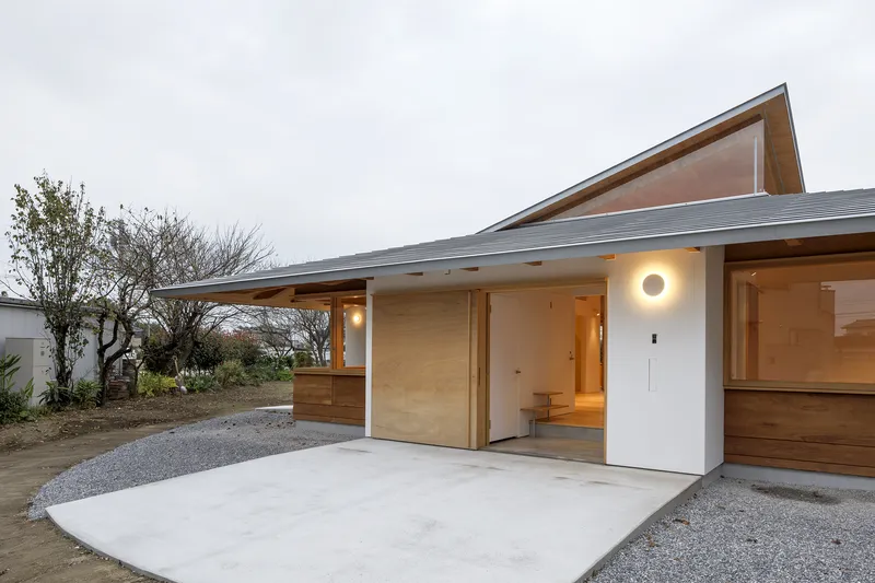 Entry courtyard with concrete paving and angled roof eave at twilight