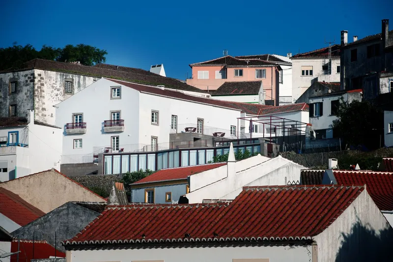 Hillside view showing glazed addition with steel frame above terraced rooftops