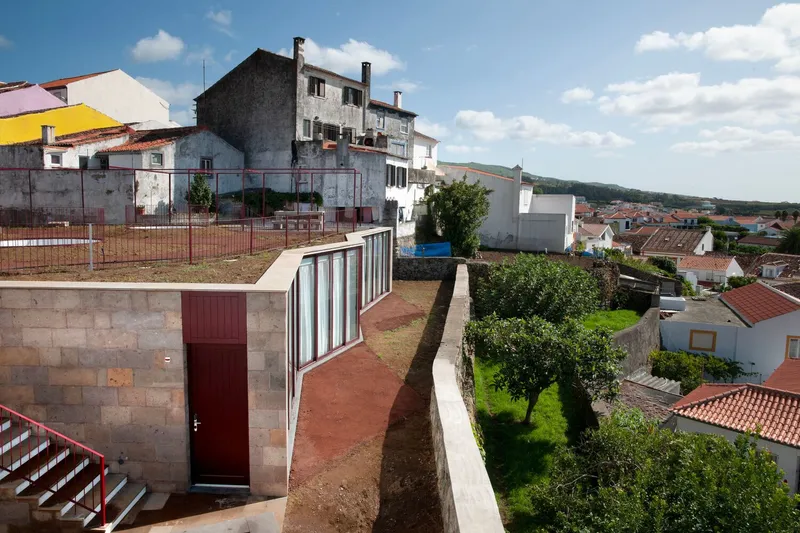 Rooftop terrace with maroon door and curved glazed wall overlooking village below