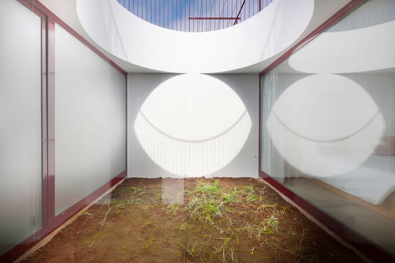 Interior courtyard with circular skylight above planted bed and white reflecting panels
