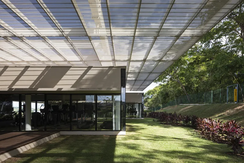 Striped shadow pattern from the translucent roof grid falling across the glass walls and lawn