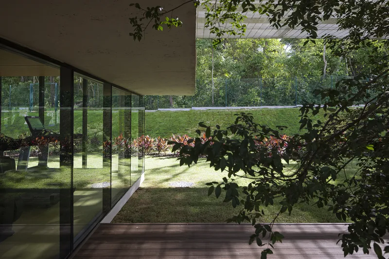 Corner of the glazed pavilion with reflections of foliage and the garden in the floor-to-ceiling windows