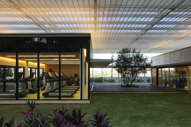 Courtyard view showing glass-enclosed gym pavilions separated by a planted lawn and tree