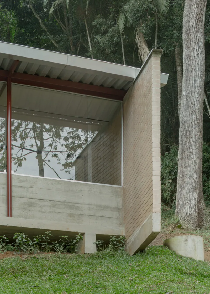 Exterior corner detail showing cantilevered concrete base, buff brick wall and corrugated soffit among palm trees