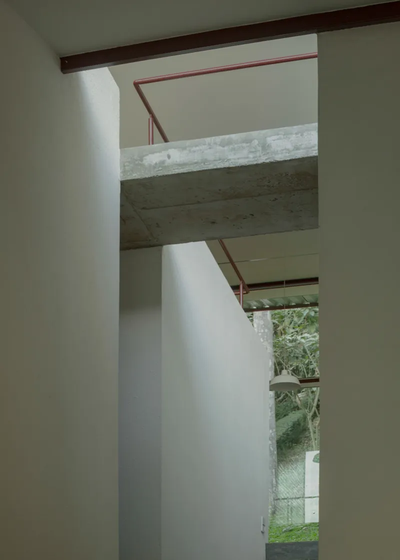 Exposed concrete beam spanning above white walls with a view through to the green garden beyond