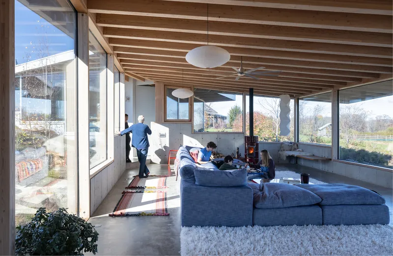 Living room with concrete floor and timber ceiling where occupants gather on a winter afternoon