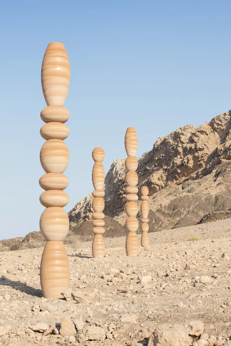 Cluster of laminated wood columns with alternating light and dark grain against a rocky hillside
