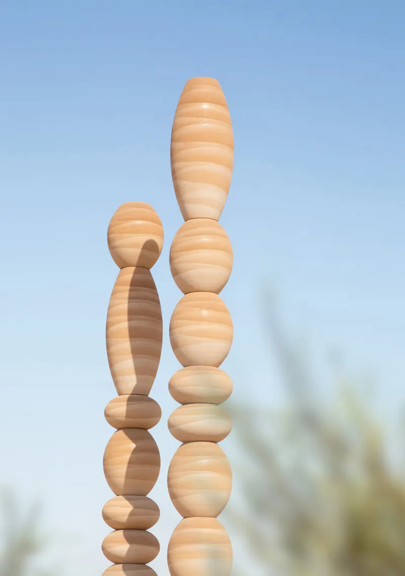 Close view of two laminated wood columns with horizontal banding against a clear sky