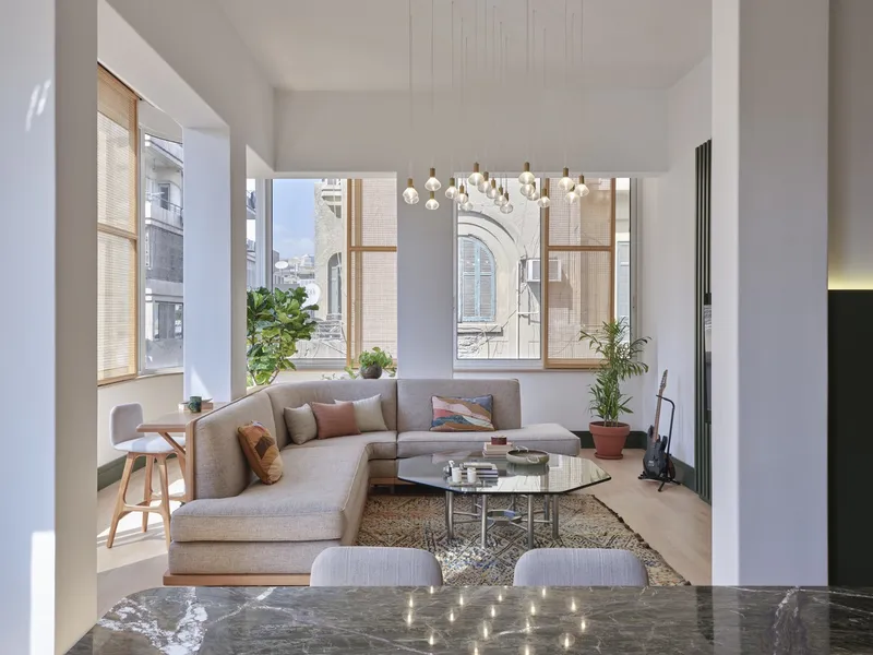 Sitting area seen from kitchen with glass coffee table and sectional sofa beneath high ceiling