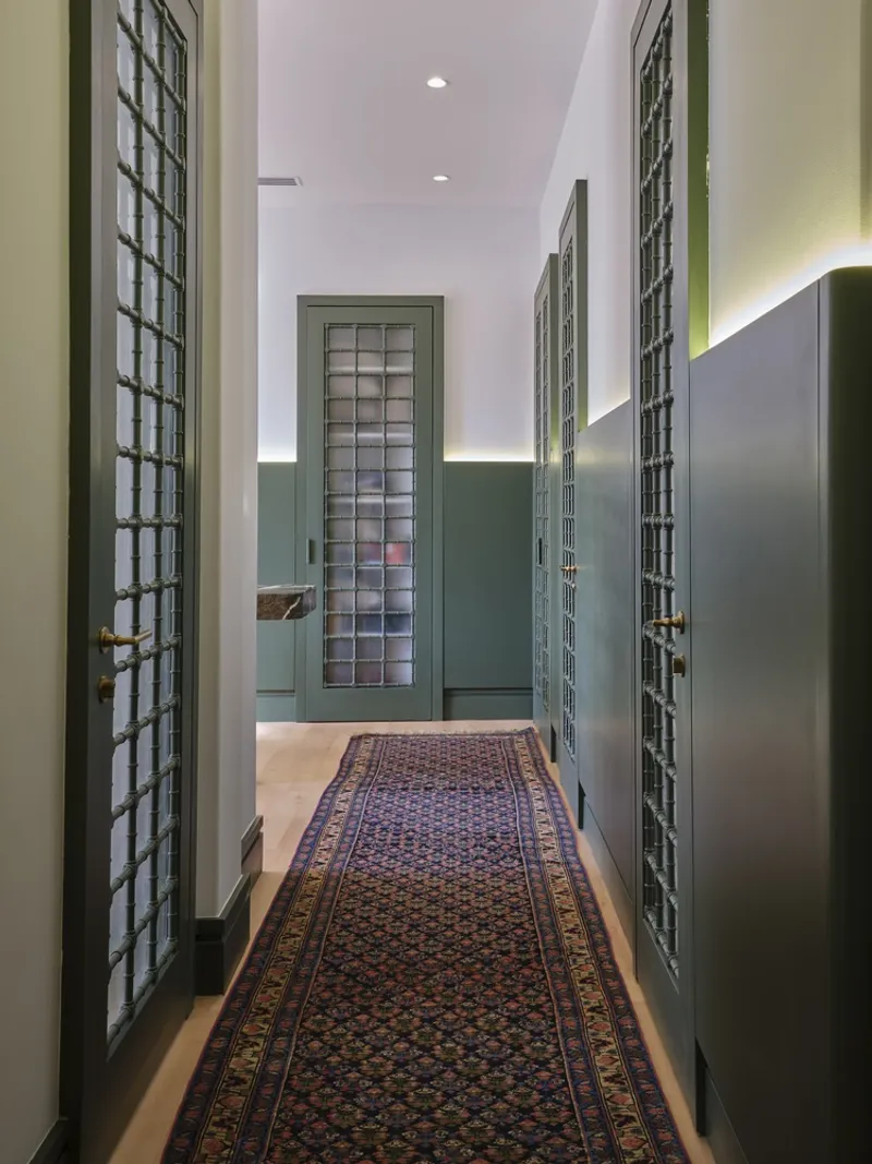 Corridor with green wainscoting, glass block doors and concealed uplighting along the walls