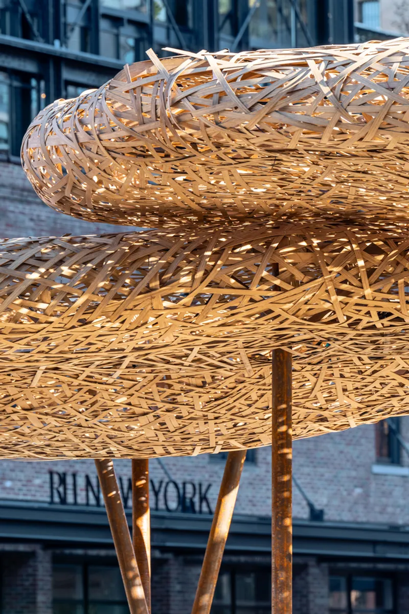 Detail of layered woven timber canopy structure with splayed bronze supports visible beneath