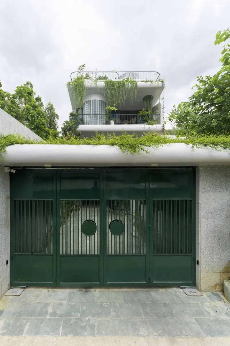 Dark green ribbed metal entry gate with circular porthole details below planted roof edge