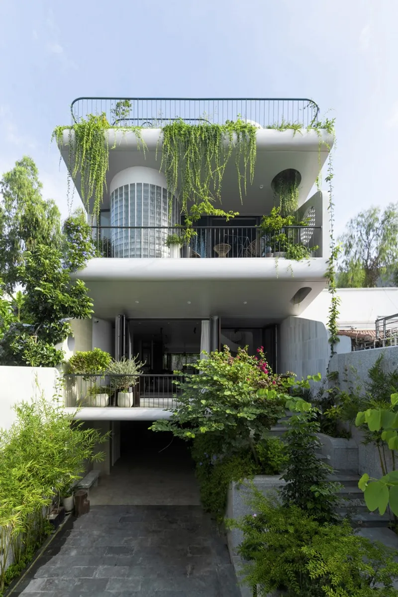 Garden facade showing three levels of planted balconies with trailing vegetation under overcast sky