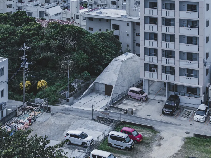 Elevated view of the pyramidal concrete roof surrounded by apartment towers and parked cars at dusk