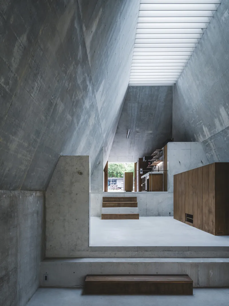 Upward view showing angled concrete walls converging toward a linear skylight above split levels