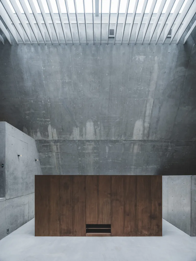 Freestanding timber volume inserted within a concrete room beneath a slatted skylight