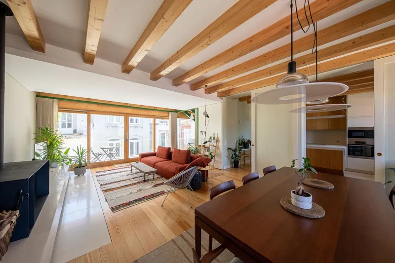 Interior view showing timber ceiling joists above an open living area with large glazed doors
