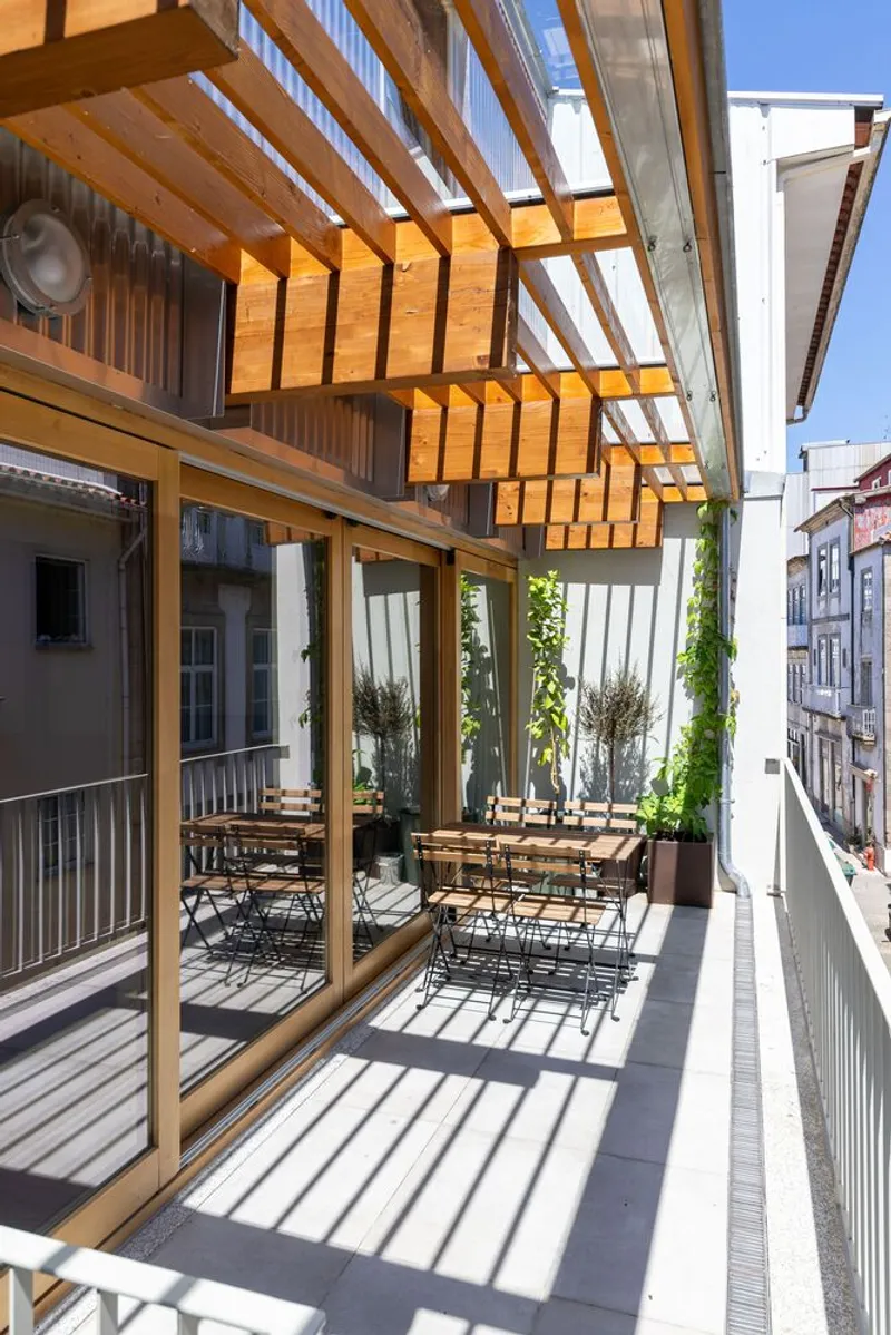 Timber pergola over a terrace with folding chairs casting shadows in bright midday sun