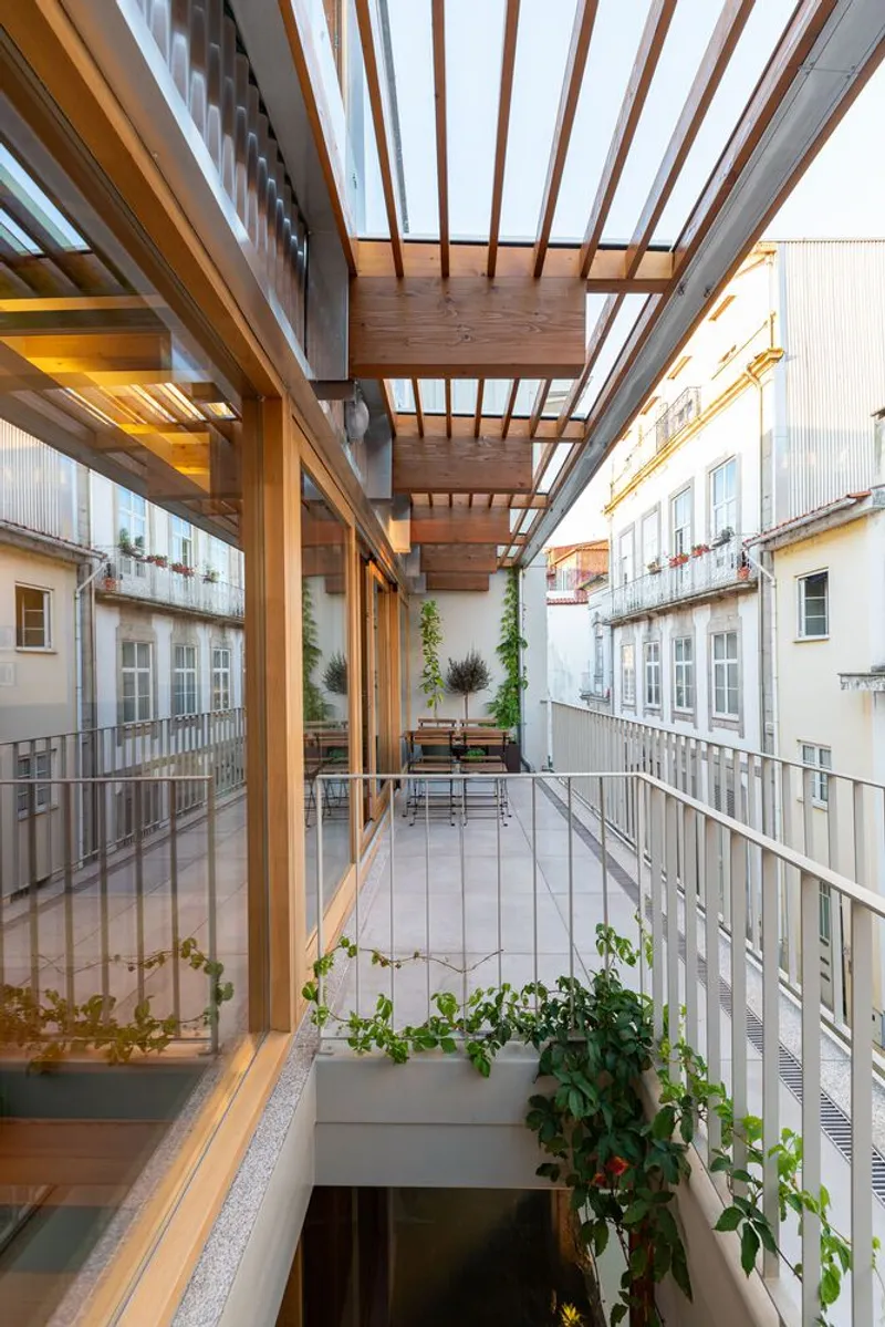 Multi-level balcony structure with timber beams and pergola framing the adjacent courtyard facades at dusk