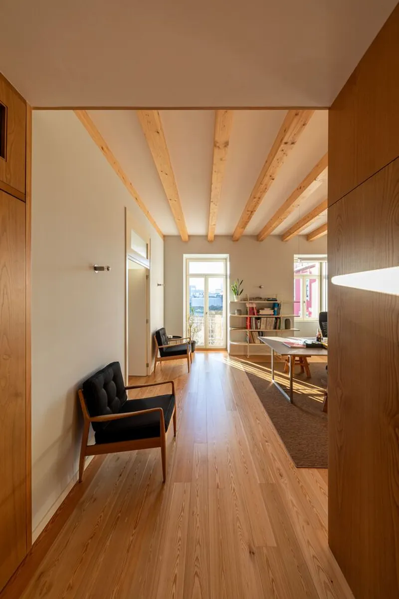 Hallway with timber flooring and exposed ceiling beams lit by afternoon sunlight through doorway