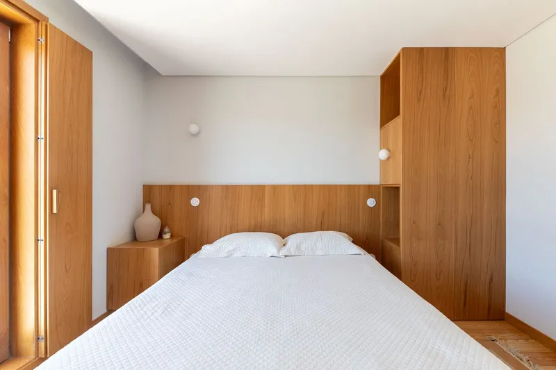 Bedroom with integrated timber headboard and wardrobes against white walls and ceiling